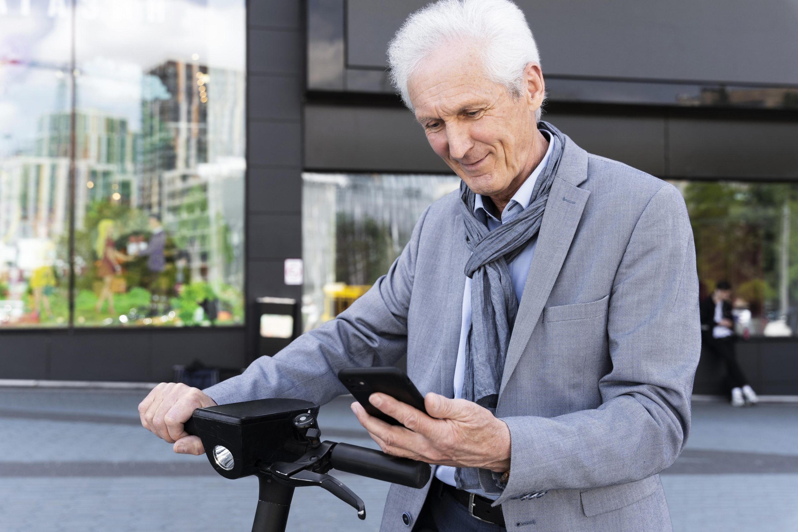 older-man-city-with-electric-scooter-using-smartphone-scaled